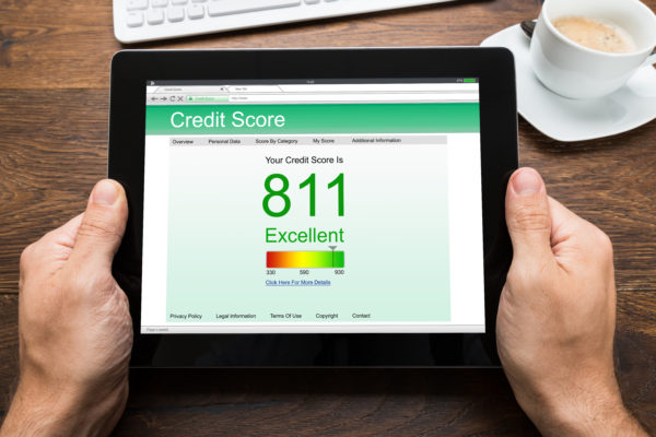 Close-up Of Person Hands With Digital Tablet Showing Credit Score At Desk
